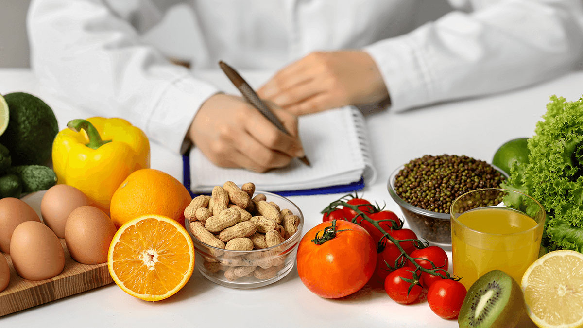 A male nutritionist making notes with healthy food around his table